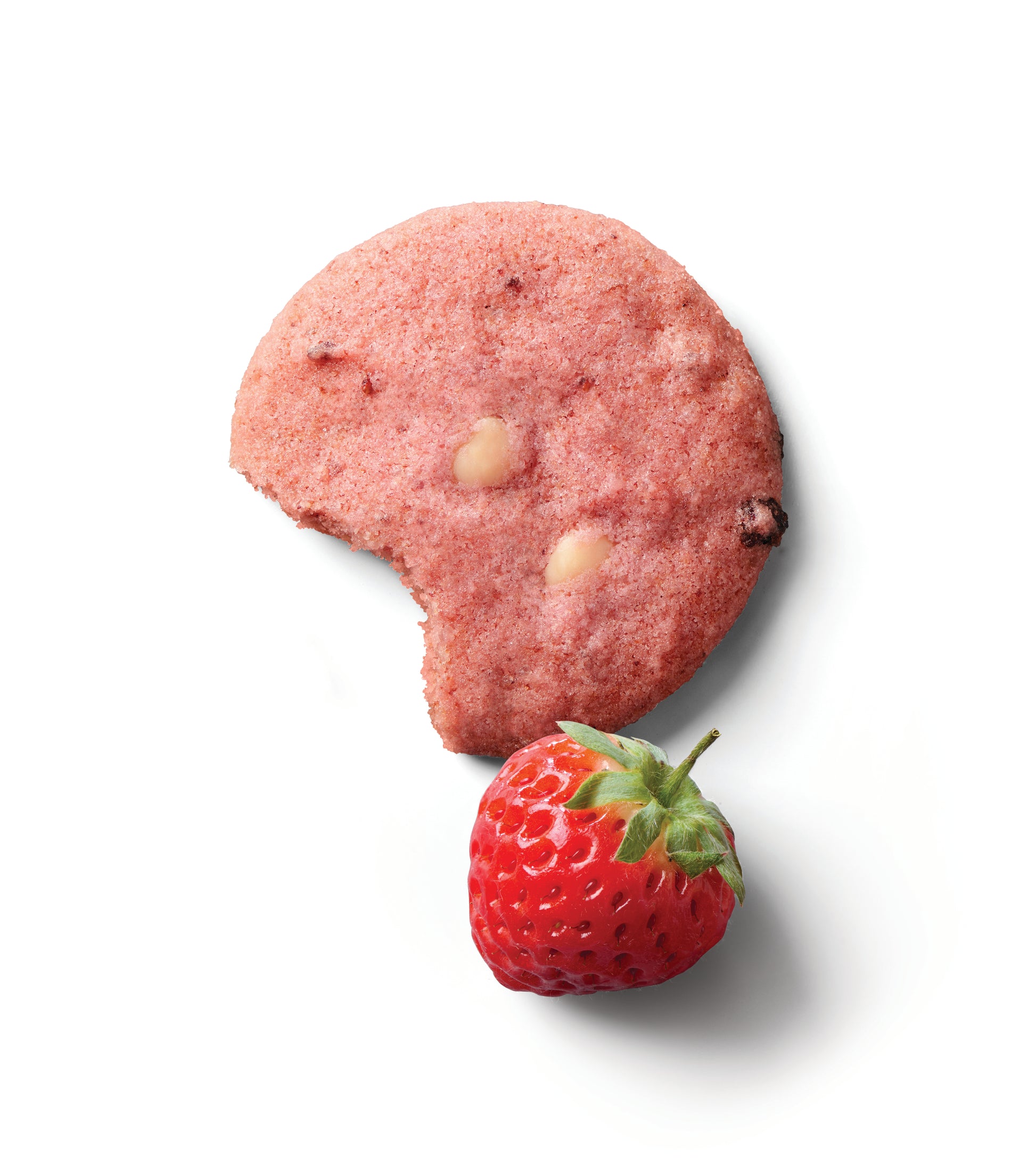 Thin crispy strawberry shortcake cookie with white chocolate chips next to a fresh strawberry