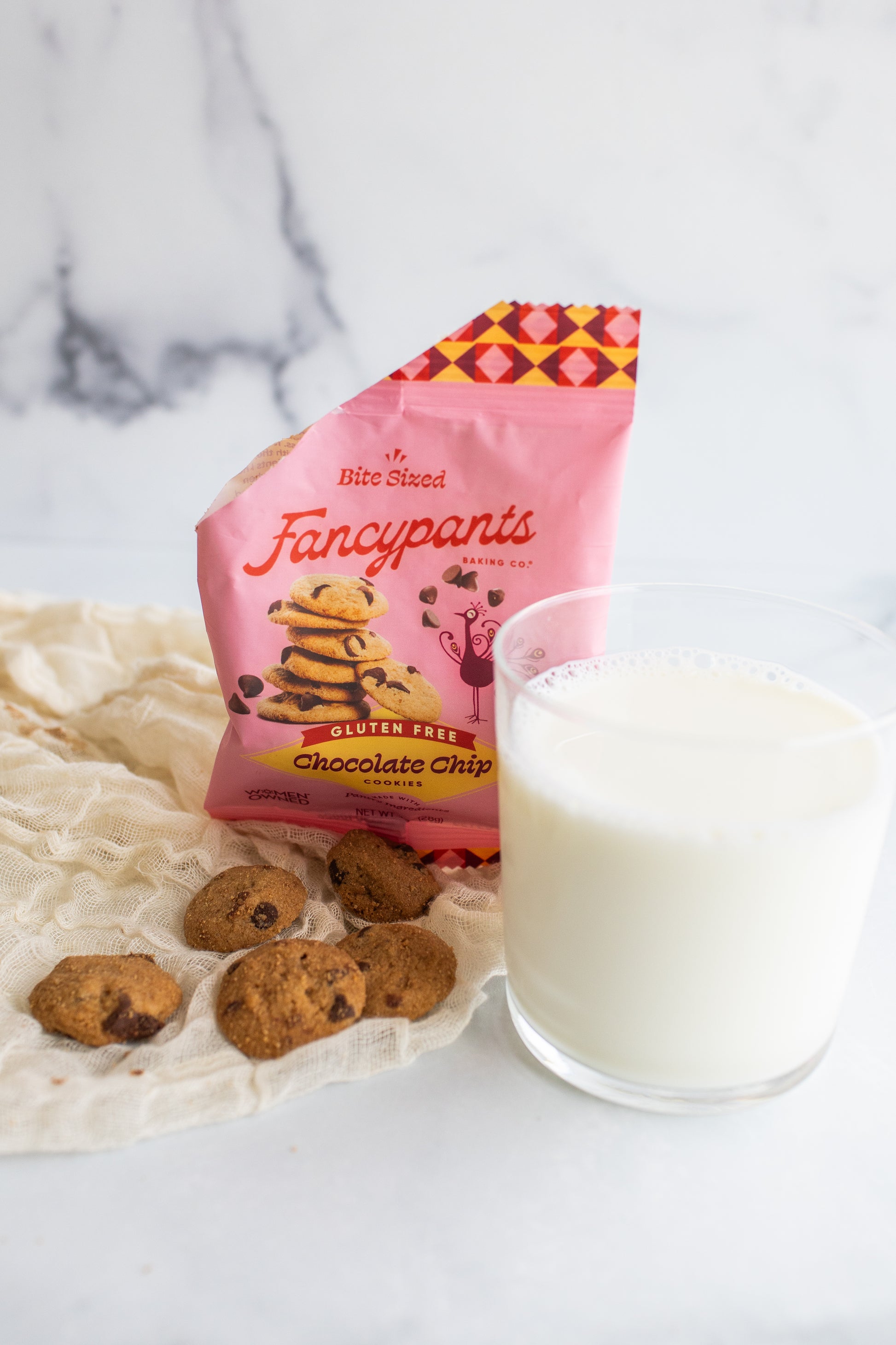 Bag of 'Fancypants' cookies with cookies and a glass of milk on a marble surface